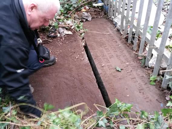 A volunteer uncovers Mary Anne Rawson's grave.