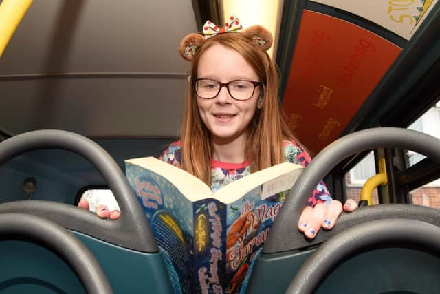 Isabel reads a book at the opening of 'Buster', a bus which has been converted into a library, at Athelstan Primary School.