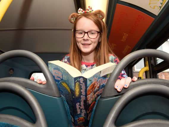 Isabel reads a book at the opening of 'Buster', a bus which has been converted into a library, at Athelstan Primary School.