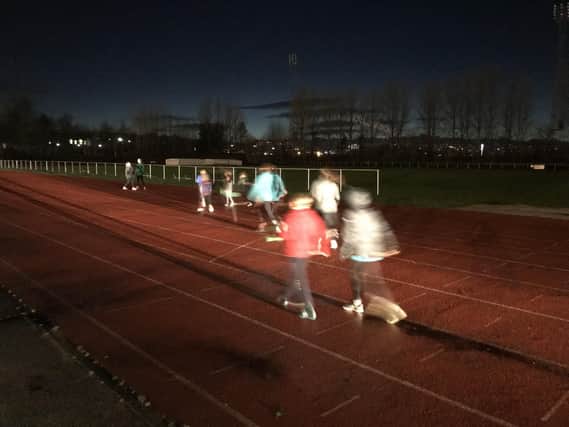 Young athletes training in near darkness at Sheffield Hallam University City Athletics Stadium, where parents resorted to using car headlights to illuminate the track