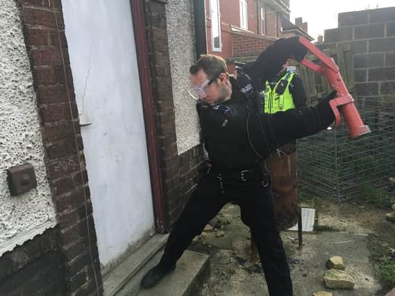 Police batter a door in Fox Hill, Sheffield, during a raid