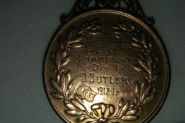 The medal is engraved with 'J.Butler'