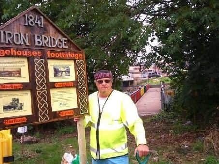 John Errington with a signpost at the footbridge he lovingly renovated