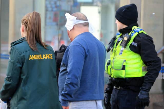 The injured man is led away from the scene by paramedics. Pictur: Chris Etchell / The Star.