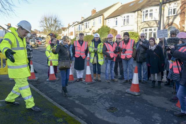 Campaigners look on as council contractors prepare the road around a tree for remedial work as part of the new agreement