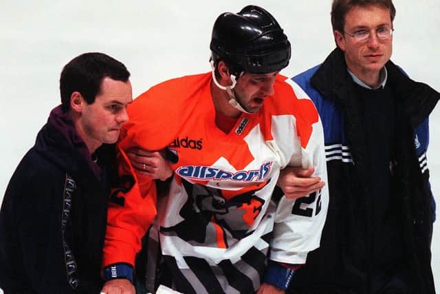 Andre Malo is helped off the Ice after injuring his face on the boards.