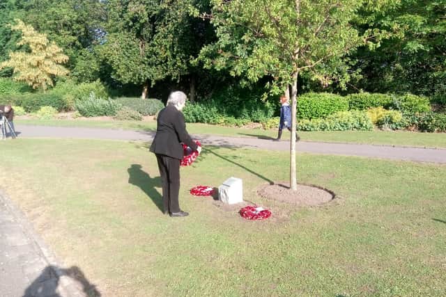 Pat Davey lays a wreath at the tree.
