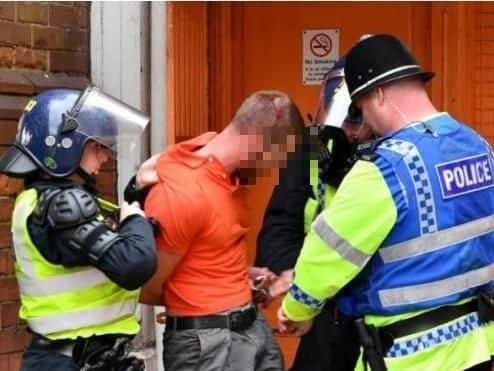 A fan is arrested during clashes between Sheffield United and Grimsby Town supporters.