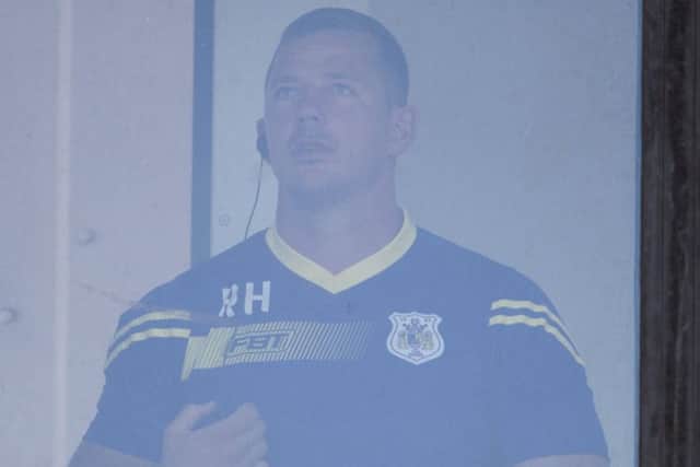 Dons coach Richard Horne watches on from the comms booth