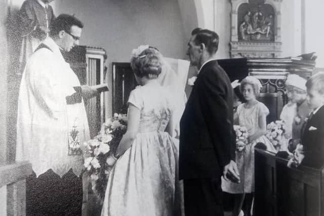 The priest leads the mystery couple's service while family look on.