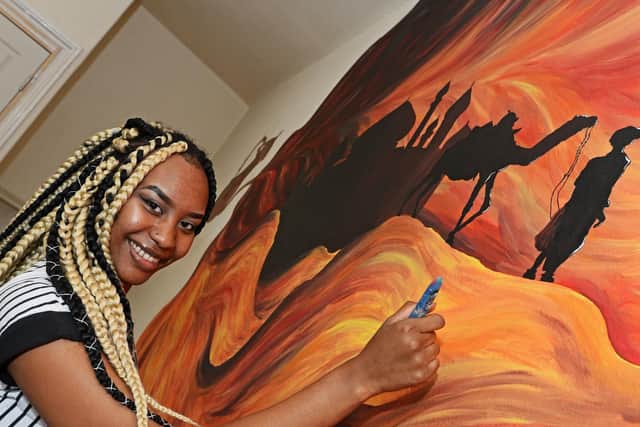 Allia Adam with the mural she painted inspired by the Arabic language