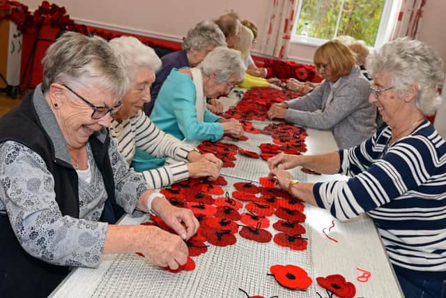 Church Memebers pictured tying the handmade poppies to a cascade