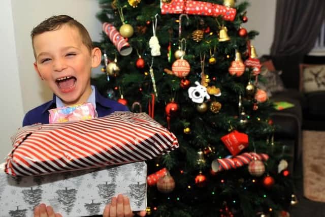 Jacob Pool 5 from Seacroft, Leeds , with some Christmas presents by his Christmas tree.