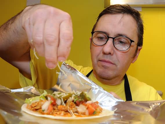 Richard Golland, of Street Food Chef, inside their third shop on Glossop Road, sprinkles cheese onto a taco. Picture: Andrew Roe