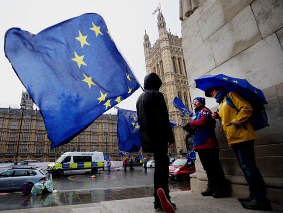 Remain supporters shelter from the wind and rain across the street from the Palace of Westminster, London. Photo: Jonathan Brady/PA Wire