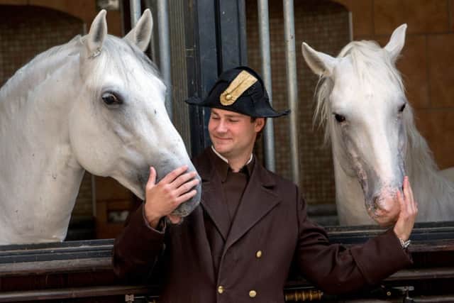 Florian Bacher, a rider from The Spanish Riding School of Vienna, poses with two Lipizzaner stallions as they peer out if their stables outside the Austrian capital's Imperial Palace. PRESS ASSOCIATION Photo. Picture date: Wednesday September 10, 2014.  The Spanish Riding school of Vienna is coming to the UK  to perform shows in Sheffield and London  with Great Britain Olympic medalist Carl Hester and paralympic medalists Lee Pearson and Natasha Baker. Photo credit should read: Steve Parsons/PA Wire