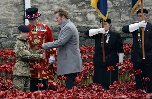 Artist Paul Cummins hands the final poppy to be planted to Cadet  Harry Hayes, 13. Photo by Andrew Matthews/PA Wire
