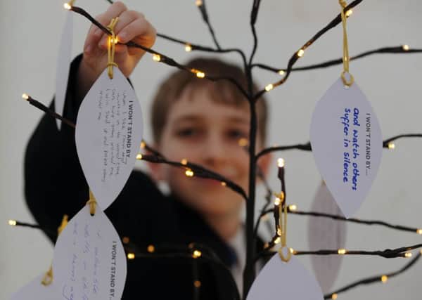 Holocaust Memorial Day event - Don't Stand By - held in All Saints Square in Rotherham.Oakwood High School pupil Thomas Barker adds his pledge to the  on a symbolic ''message tree''. Picture Scott Merrylees