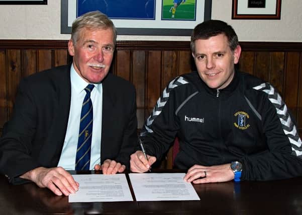 Chris Hilton signs his new deal, watched by Mick Grimmer, club secretary. Pic: Peter Revitt