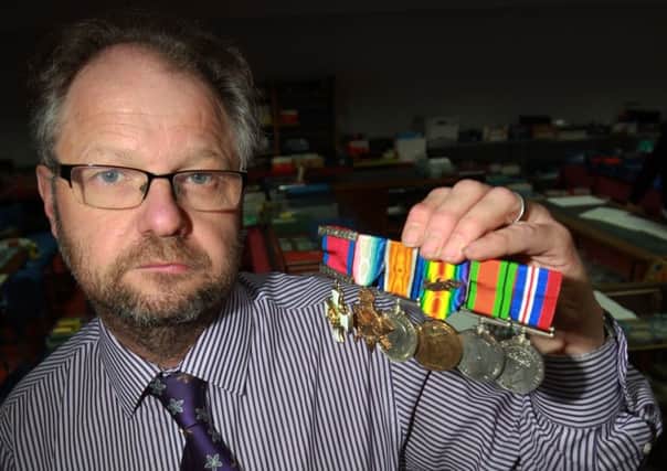 A collection of over 1000 military medals is being sold by the Sheffield Auction Gallery. Pictured is valuer John Morgan and one of the medals.