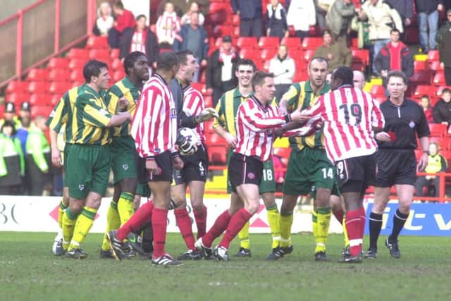 Patrick Suffo is held back by players.