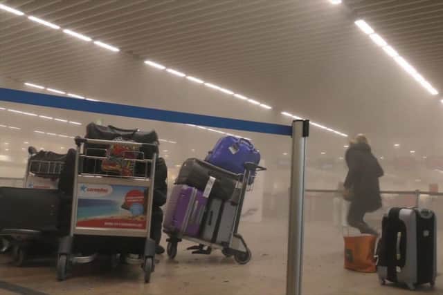 In this photo provided by Ralph Usbeck an unidentified traveller runs in a smoke filled terminal at Brussels Airport, in Brussels after explosions Tuesday, March 22, 2016. Authorities locked down the Belgian capital on Tuesday after explosions rocked the Brussels airport and subway system, killing  a number of people and injuring many more. Belgium raised its terror alert to its highest level, diverting arriving planes and trains and ordering people to stay where they were. Airports across Europe tightened security.  (Ralph Usbeck via AP)