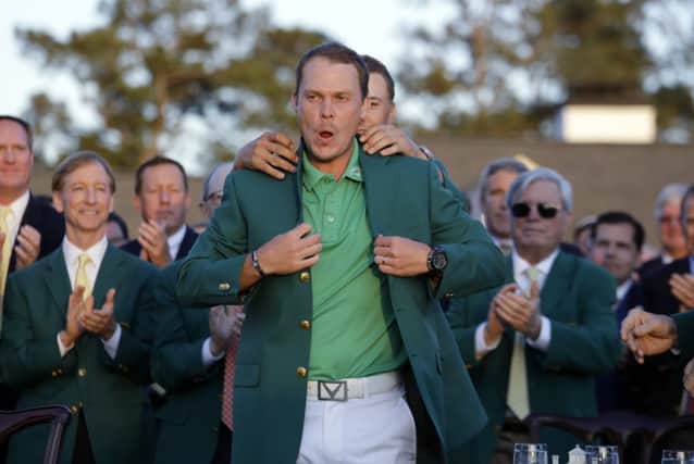 Defending champion Jordan Spieth, left, helps 2016 Masters champion Danny Willett, of England, put on his green jacket following the final round of the Masters