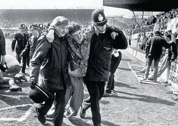 Andy Frith (right) helps an injured fan at the Hillsborough disaster