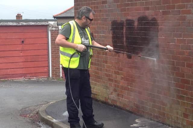 David Ogle, Friends of High Green Parks and Streets community group, cleans graffiti from a wall on Foster Way, High Green.