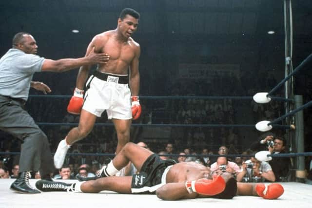 Ali is held back by referee Joe Walcott after knocking out challenger Sonny Liston in the first round of their title fight in Lewiston, Maine, in 1965