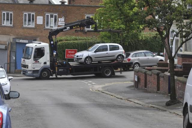 Cars being towed away from the side of the road on Huntingtower Road at Greystones in Sheffield to resurface the road