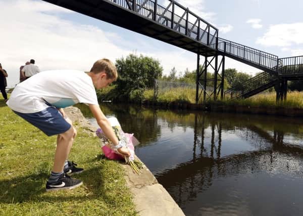 People bring flowers to the scene in Rotherham, South Yorkshire, where an 11 year old boy has drowned in a canal. Pic: Glen Minikin