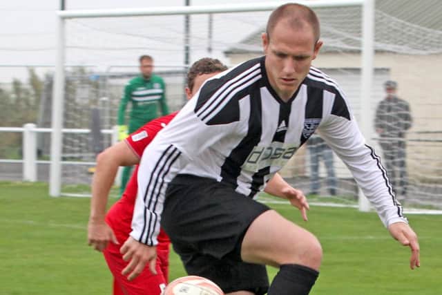 Dale Kelly, who scored a hat-trick in Penistone Church's remarkable 9-5 home win over Grimsby Borough, holds off a visiting defender. Photo: Ian Revitt