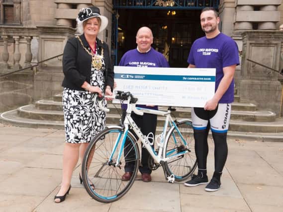 Jordon Fox (right) and his cycling companion Ray Mason (centre) presented Coun Fox (left) with a cheque for 850 outside Sheffield Town Hall
