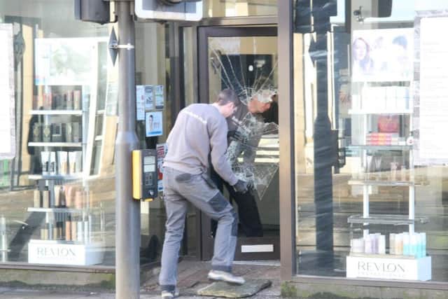 Shop fitters working on the smashed door after raiders made their way in during the night. Picture: George Torr/The Star