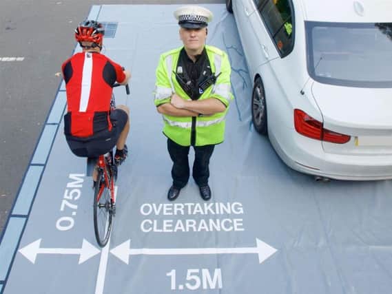 A West Midlands Police officer illustrates the safe clearance for drivers overtaking cyclists