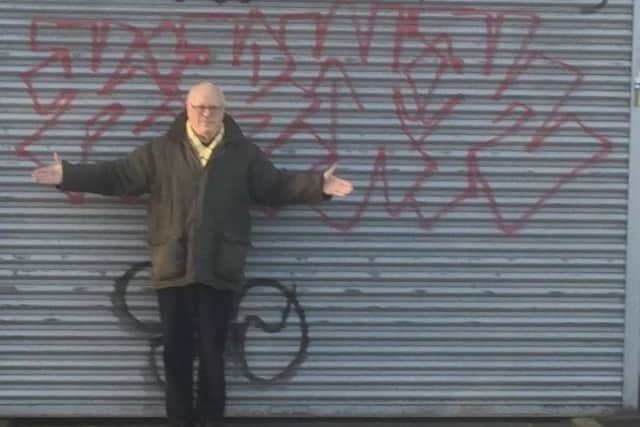 Andrew in front of a graffiti-daubed shutter in Harvest Lane