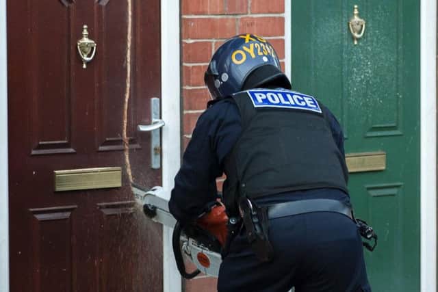 An officer uses a chainsaw to gain access to a house in Rotherham. Picture: Paul Drabble