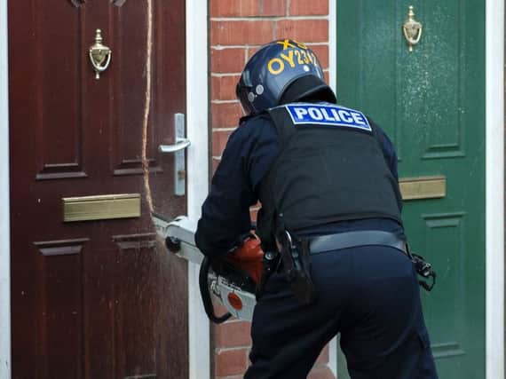 An officer uses a chainsaw to gain access to a house in Rotherham. Picture: Paul Drabble