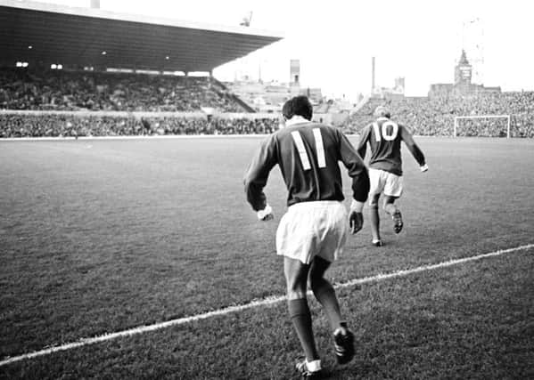 George Best of Manchester United (11) runs onto the pitch, following Denis Law (10) at Old Trafford, circa 1964.