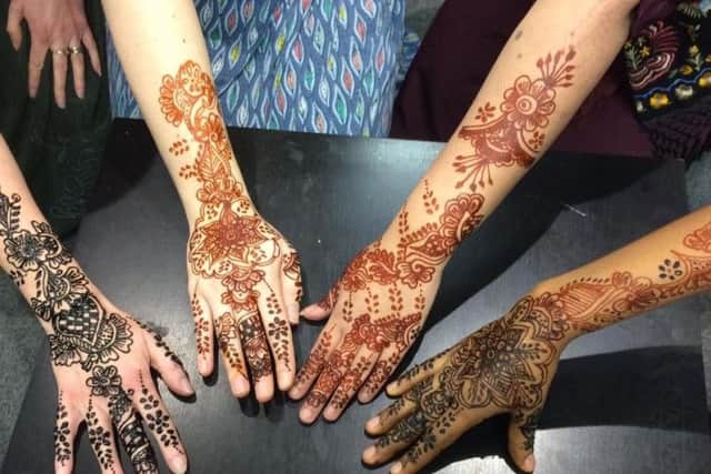 Human trafficking victims supported by the Snowdrop Project show off the henna tattoos they had done at the charity's Christmas party