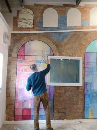 A mural at the Bamforth Building which shows the landscapes of Sheffield through nine windows. It was painted by artist Michael Harter for the Burton Street Foundation. Photo shows Michael at work.