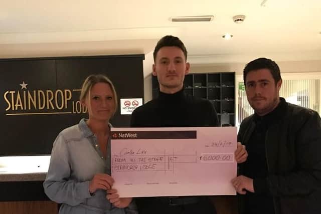 Staindrop Lodge barman Connor Brunt presents one of two cheques to Carter's mum Becki and step dad Chris
