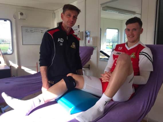 Rovers physio, Alex Dalton, with defender, Joe Wright, using the product which is called VibraCool.