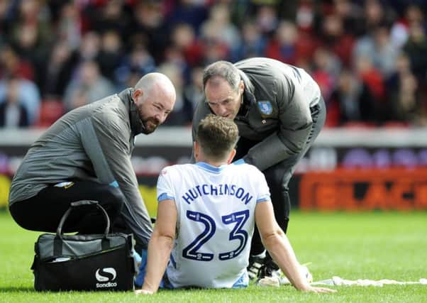 Sam Hutchinson is attended to by Sheffield Wednesday physio Paul Smith and club doctor Richard Higgins during the match against Barnsley