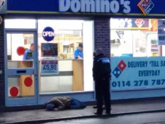 Police attend to a man outside Domino's on West Street in Sheffield city centre