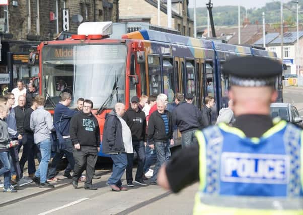 Police officers on duty in Hillsborough ahead of the derby game as fans disembark from a tram. Picture: Dean Atkins