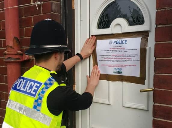 An officer attaches a notice to the door of the property
