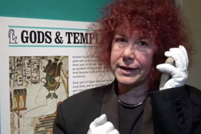 Guest curator TV Egyptologist Prof Joann Fletcher demonstrates the use of an ancient Egyptian 'mobile phone', a Stela used to talk to the gods, in one of the many video's that also pops up using the Aurasma app on the poster