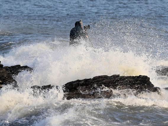 A man taking photographs gets caught by crashing waves at High Rock in Portmarnock, Dublin. Brian Lawless/PA Wire